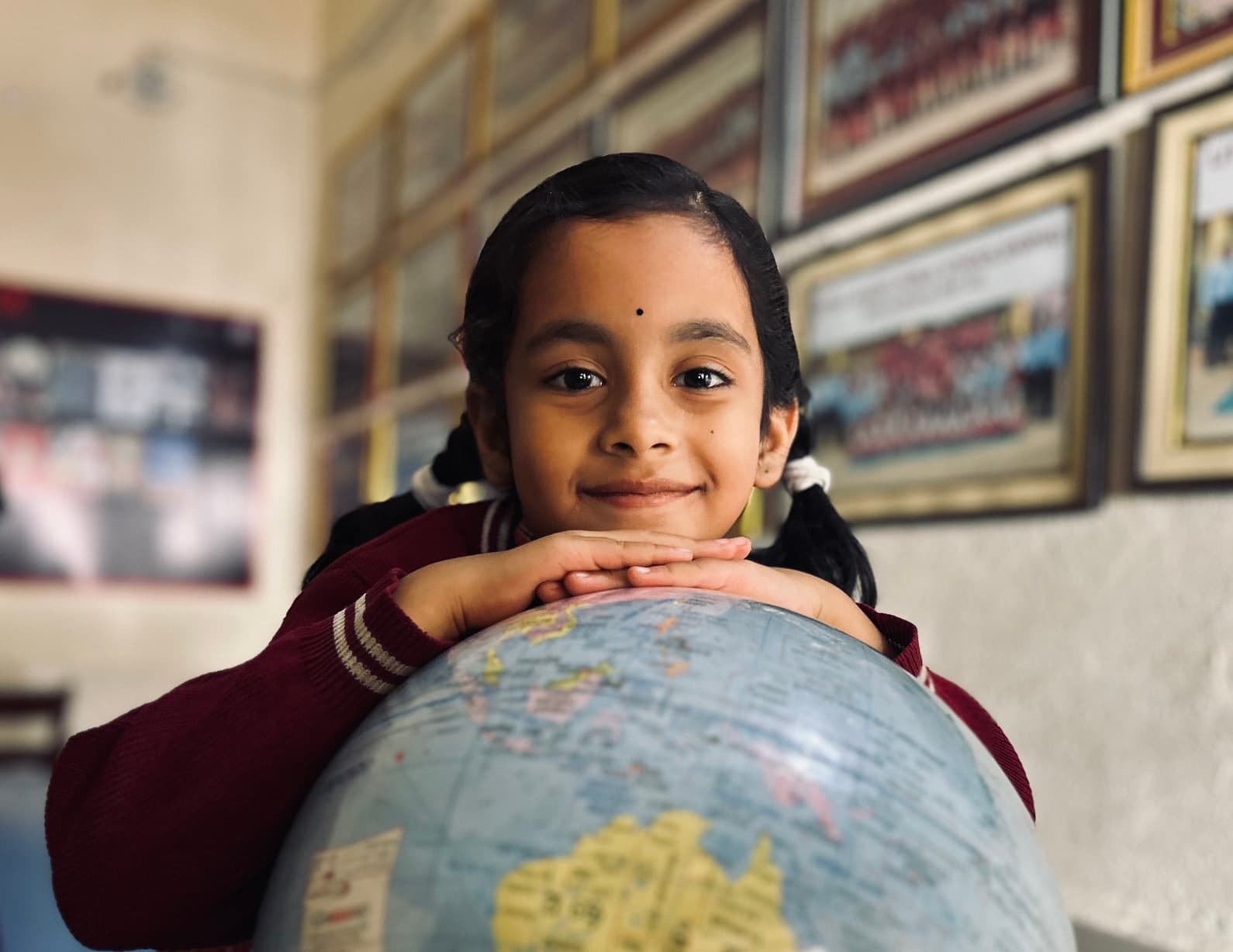 A Little Angels student resting on a globe